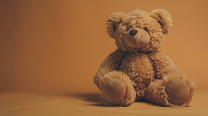 Soft plush teddy bear sitting alone on an orange background, evoking warmth and childhood nostalgia.