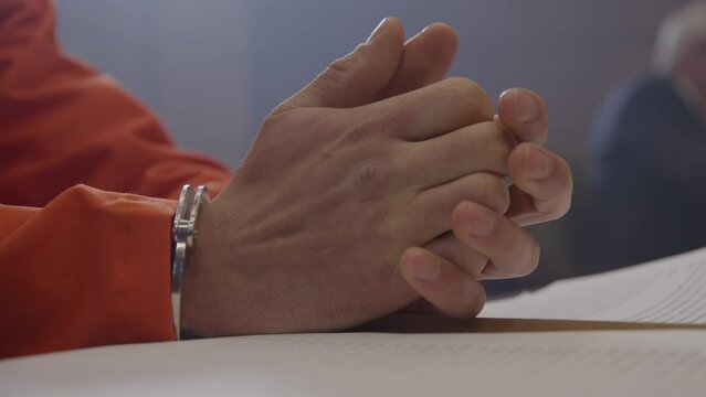 Worried inmate in handcuffs in trial before judge