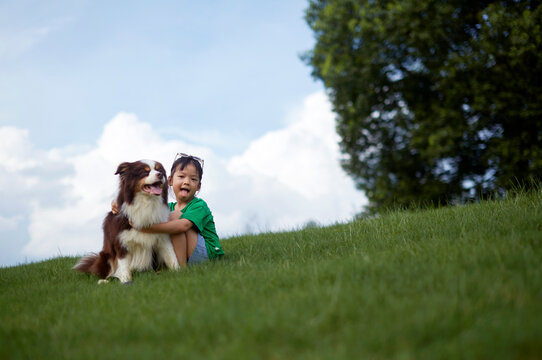 Asian girl, playing with her dog on the grass in the park