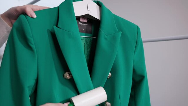 Using Adhesive Lint Roller On Green Dry-cleaned Suit At Laundry Shop. slow motion shot