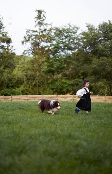 Asian girl, playing with her dog on the grass in the park