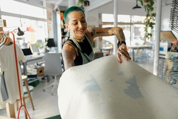 Creative female worker preparing screen printing film for using on printing machine in a workshop