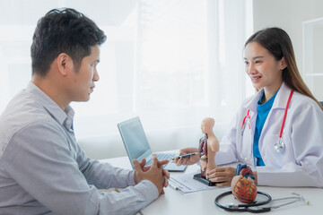 Obraz premium Heart disease. Female doctor gives advice on heart disease treatment. A cardiologist while giving a consultation shows an anatomical model of a human heart to an elderly patient talking about heart di