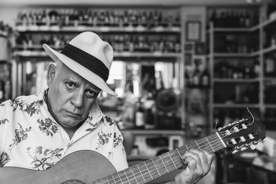 Old serious cuban man with spanish guitar in local cafe