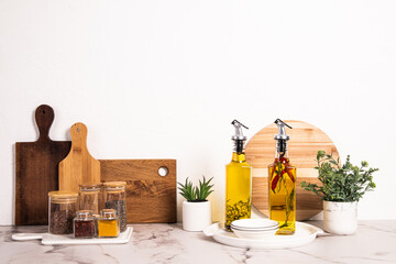 Stylish kitchen background with spice jar set, wooden cutting boards and two oil dispenser bottles...