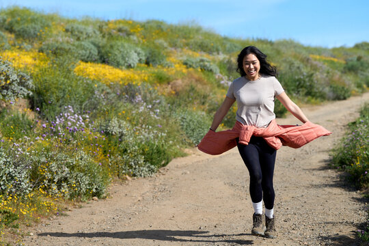 A girl of south east asian descent runs down a path in nature