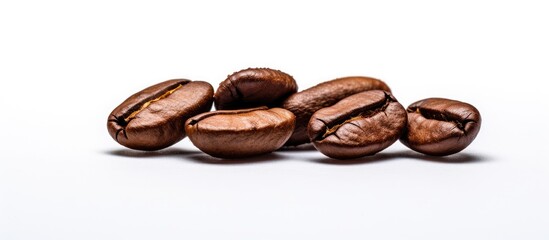 A close-up shot of a pile of dark brown coffee beans resting on top of a white table. The beans appear freshly roasted and exude an enticing aroma, highlighting the energizing caffeine they contain.