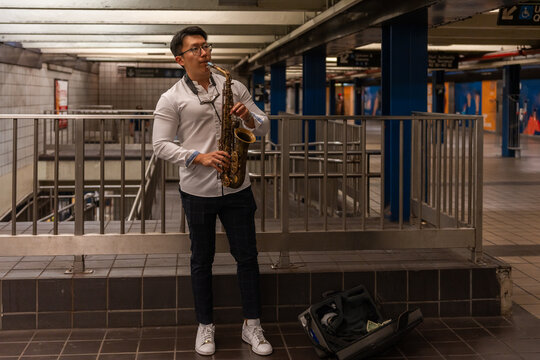 Asian Man Playing The Saxophone In The Metro Of New York.