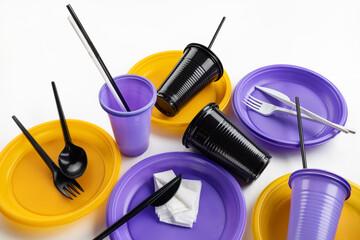A set of disposable plastic tableware in lilac, yellow and black colors. Ecology and plastic waste...