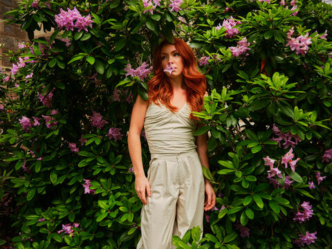Young red-haired girl in a bush of flowers
