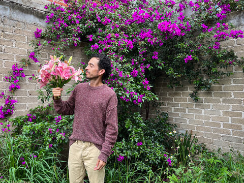 A man smelling an arrangement of pink lilies