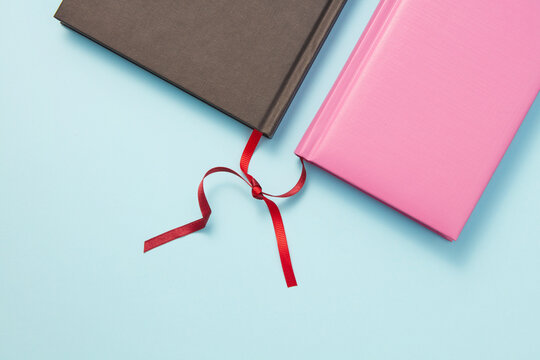 Two books with intertwined bookmarks.