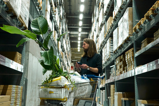 A long-haired man browses goods in a home market