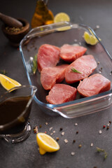 Pieces of Fresh tuna Fish fillet in glass cooking dish and soy sauce marinade in a gravy boat