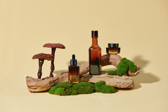 Set of amber glass cosmetic bottle and jar of moisturizer on podium.