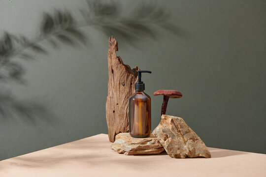 Brown amber glass bottle on podium on beige background.