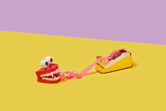 Red plastic jaws eating curly sticky tape.