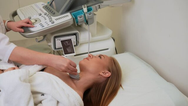 Top view of unrecognizable female doctor performing ultrasound examination of lymph nodes of patient neck. Diagnosis and treatment of autoimmune thyroiditis concept. Shooting in slow motion.