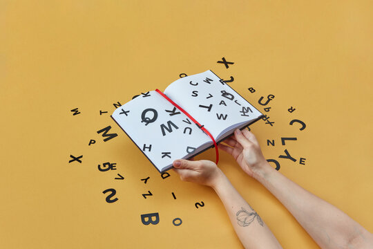 Book held by woman with black paper letters.