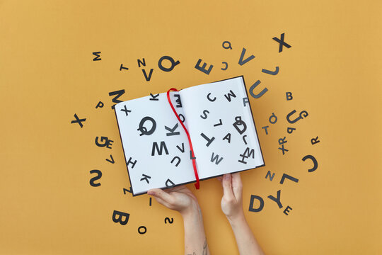 Black letters on blank book held by woman.