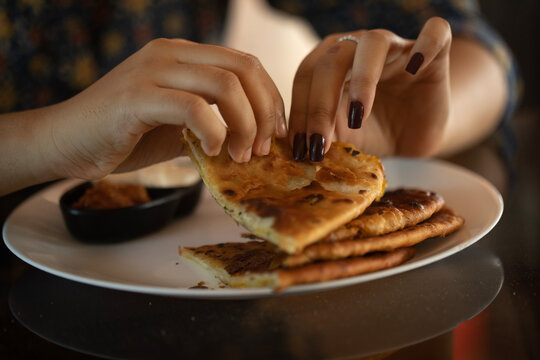 A girl taking breakfast with delicious Aloo Paratha in a restaurant 