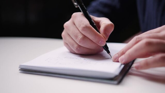 Student taking notes with a pen on a note pad