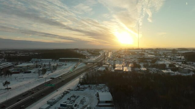Driving cars on highway in Poland at winter snow. Sunset time in suburb district of Gdynia. Aerial rising wide shot.