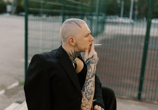 Portrait of young bald man with tattoo and broken hand