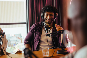 Cheerful man hosting podcast show with professional microphone in studio