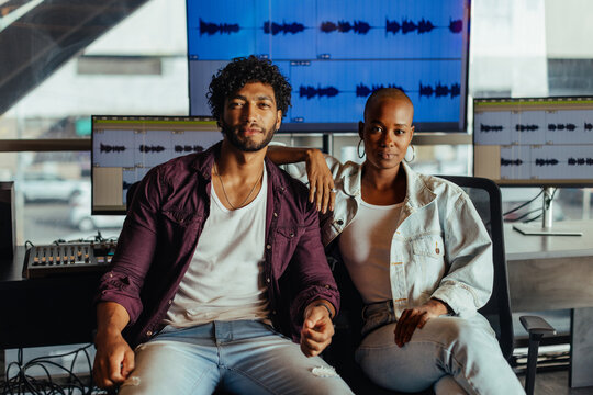 Confident creative professionals posing in a modern music studio