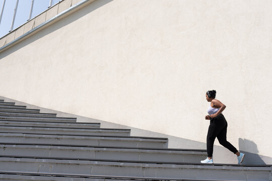 Plus Size Woman Running Up The Stairs Outdoors