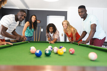 Diverse group of friends playing pool, focused on the game