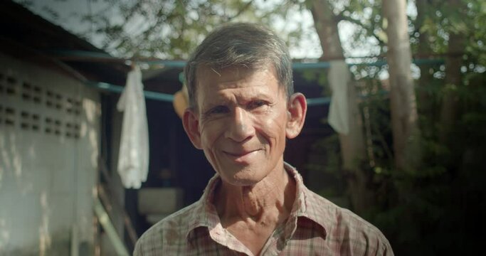 A smiling Asian man who is an elderly worker live in a poor house. Used in film concepts, humanity, documentaries and others.