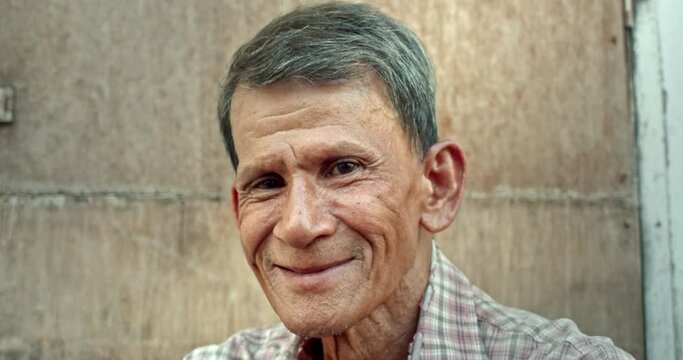 A smiling Asian man who is an elderly worker live in a poor house. Used in film concepts, humanity, documentaries and others.