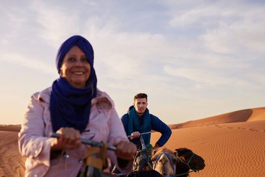 Joyful tourists explore the desert on a guided camel tour.