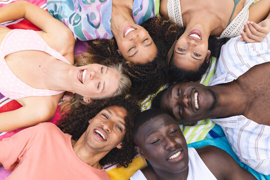 Diverse group of young adults lying in a circle, smiling upwards