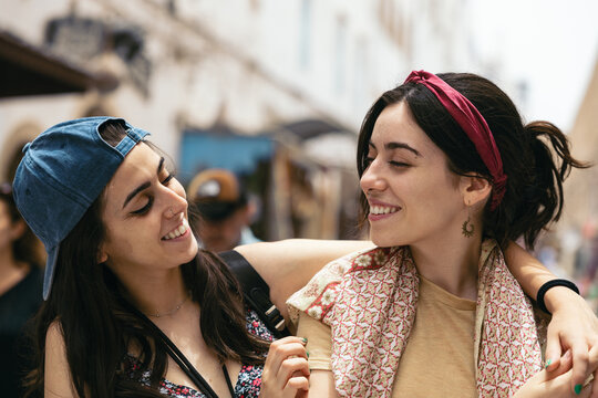 sisters looking at each other affectionately outdoors.