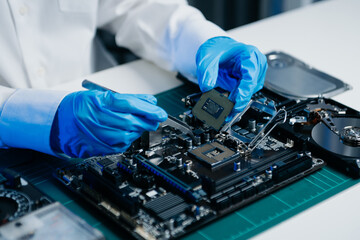 The technician is putting the CPU on the socket of the computer motherboard. electronic engineering...