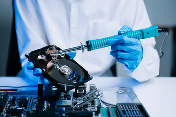  Hard disk drive on the technician's desk and a computer motherboard as a component. the concept of data, hardware, and information technology..