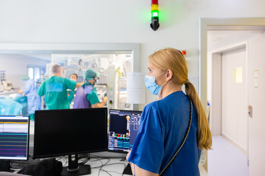Woman in mask standing next to computers in hospital