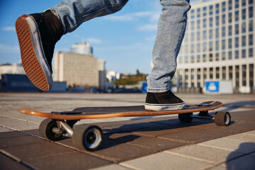 Closeup cropped view of stylish hipster man wearing sneakers riding skateboard