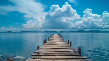  A weathered wooden dock stretching into the calm waters, under the vast canvas of a cloud-strewn blue sky. © The Image Studio