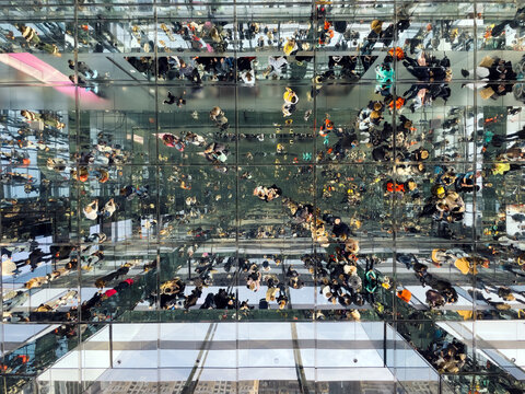People in reflective glass balcony on skyscraper