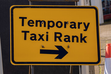 Yellow road sign with directions to the right for a temporary taxi rank location