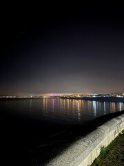 Fototapeta na wymiar Night sparkle. Night sea and city lights.