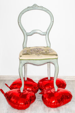 A battered antique chair stands on balloons in the shape of a heart