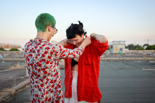 Queer friends helping each other get dressed at public abandoned place