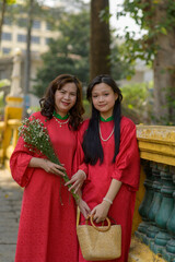 Portrait of Vietnamese mother and daughter in red Ao Dai Dress visit the pagoda on Tet holiday , Lunar new year