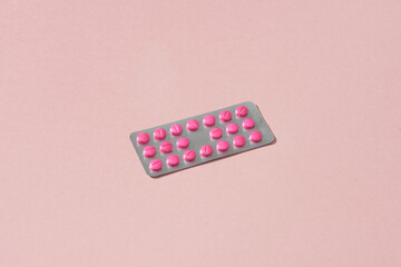 Blisters of pink pills on soft pink background.
