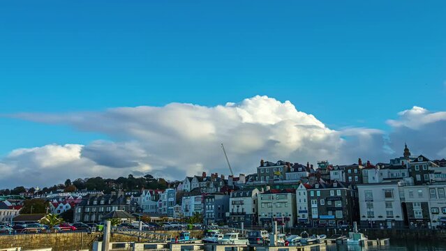 Timelapse shot of buildings along the Saint Peter Port, Guernsey, Channel Islands, UK on cloudy summer day.